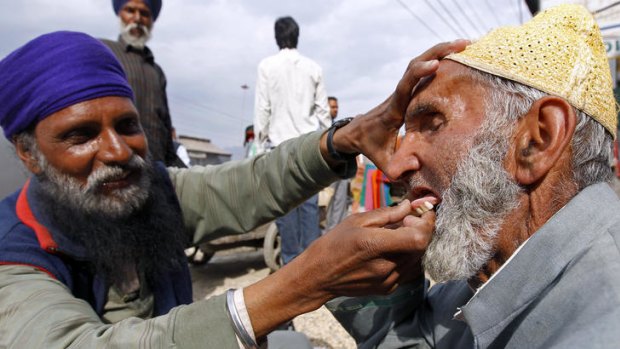Open wide: A roadside dentist inserts false teeth into the mouth of a customer in Srinagar. A new tooth can cost as little as $1.