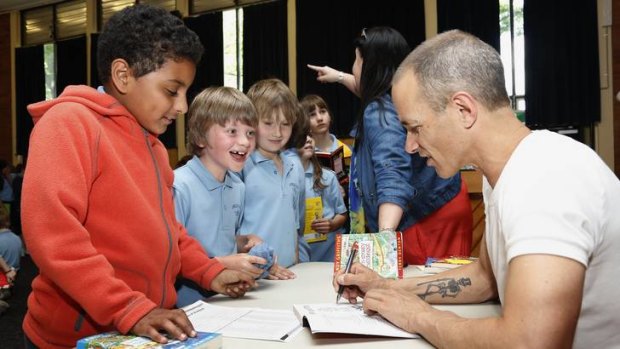 Ainslie School year 3 students Omar Algothmi, Benjamin Coram and Issac Jario get their books autographed by author Andy Griffiths following his visit to the school.