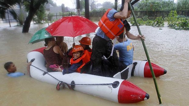 Rescuers row an inflatable boat as they help residents evacuate at a flooded village in Marikina City, Metro Manila .