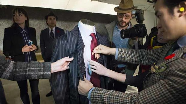 Michael Nguyen, right, co-owner of Garrison Bespoke tailors, points out bullet holes on a bulletproof suit made by the company after it was shot at from a handgun.