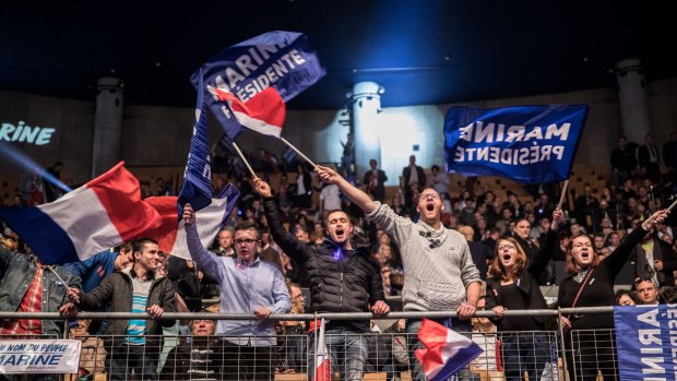 Attendees wave French national flags during an election campaign meeting with Marine Le Pen in Lille, France.
