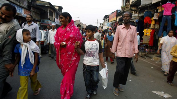 Street life ... Slumdog Millionaire star Azharuddin Ismail (white T-shirt) walks with his family near a Mumbai slum.