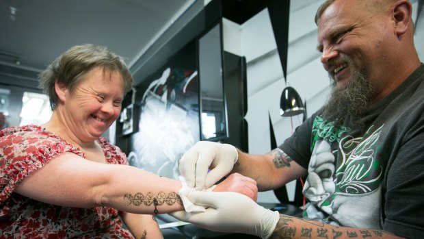Tattoo artist, Jason Ward of Muscle and Ink Tattoo gives Suzie a stick-on tattoo each week.
