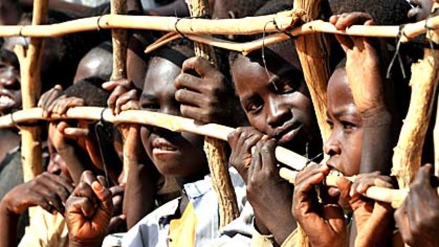 Sudanese refugee children press up against a fence in a refugee camp last month.