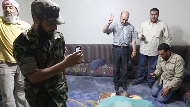 Men take pictures of Muammar Gaddafi's corpse displayed at a house in Misrata
