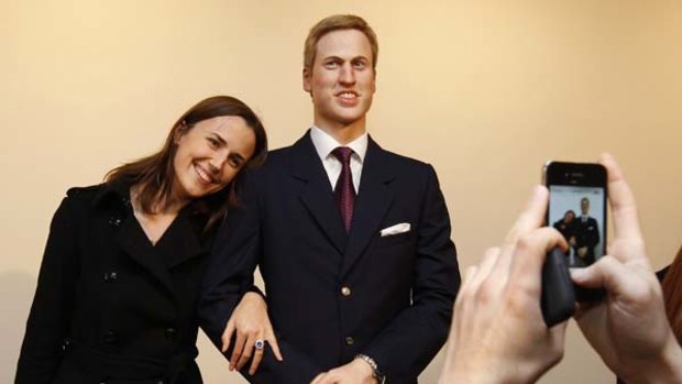 A guest poses for a photograph with a wax figure of Britain's Prince William.