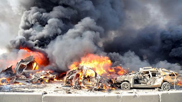 Smoke and flames spew from the wreckage of burning cars after two bombs exploded in a neighbourhood of Damascus.