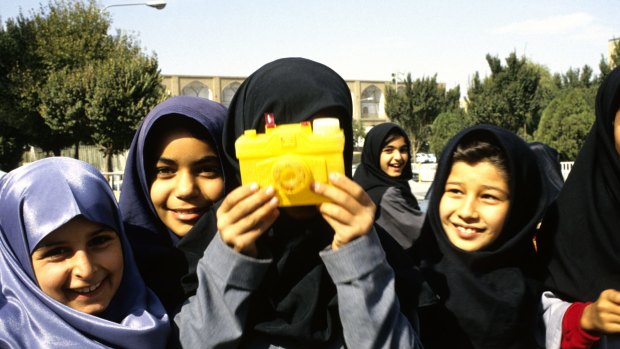 Iranian schoolgirls play with a toy camera.