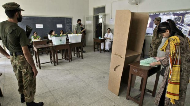 Tight security: A Pakistani woman fills out her ballot during the re-vote in Karachi.