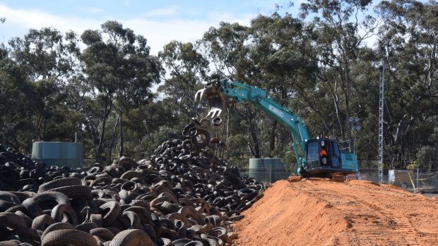 Excavators chip away at the stockpile at Stawell Tyre Yard.