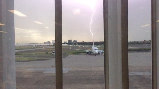 Lightning appears to strike the tail of a Qantas Boeing 737 aircraft at Sydney Airport on Thursday.