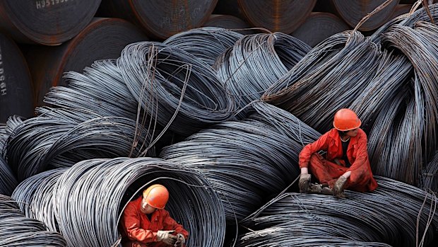 Workers take a break while sitting on a pile of steel wires at a stockyard run by the Shanghai Yirong Trading Co.