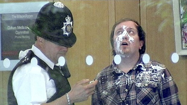 Jonnie Marbles, weairng much of the evidence,  in the hands of police after his pie stunt.