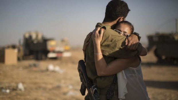 An Israeli embraces her son at a military gathering area near the Israel and Gaza border on Tuesday.