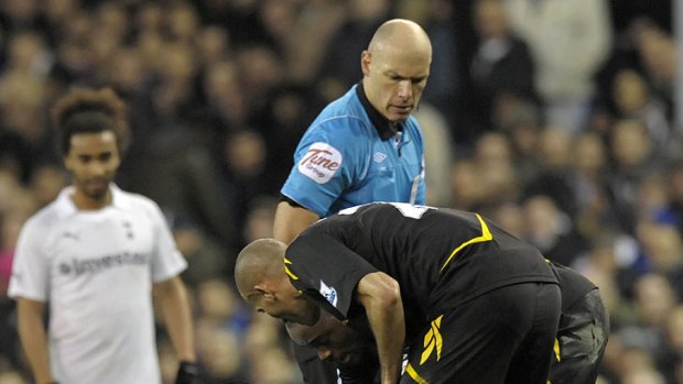 Referee Howard Webb look on as Bolton's English midfielder Fabrice Muamba is treated by medical staff.