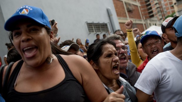 A woman who had been standing in line outside a centre in Caracas that certifies signatures for a referendum to recall President Nicolas Maduro shouts slogans against Venezuela's government after learning that the centre had closed.