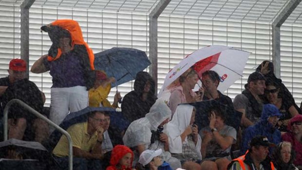 Spectators try to stay dry during the Brisbane International finals match between Robin Soderling and Andy Roddick.