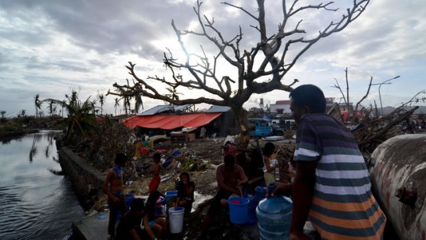 Survivors collect water from a broken water pipe in an area devastated by Typhoon Haiyan.