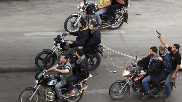 Lynch mob ... Palestinian gunmen ride motorcycles as they drag the body of a man (not seen).