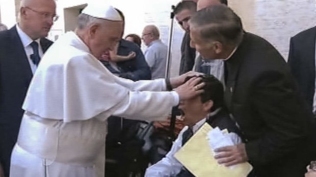 Pope Francis lays his hands on the head of a young man on Sunday, May 19, 2013, after celebrating Mass in St. Peter's Square. The young man heaved deeply a half-dozen times, convulsed and shook, and then slumped in his wheelchair as Francis prayed over him.