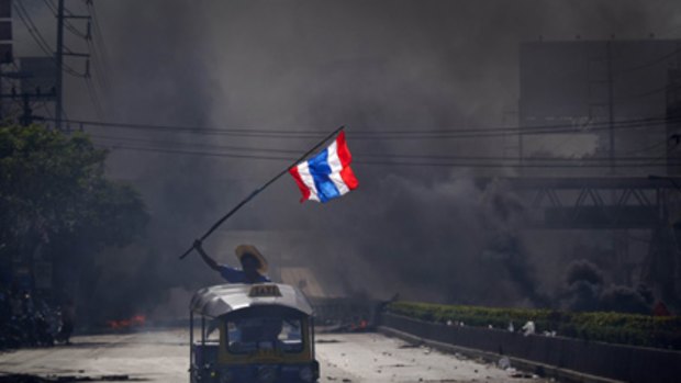 Leading from the front...an anti-government protester in a tuk tuk flying the Thai flag moves in front of a homemade security cordon in Bangkok.