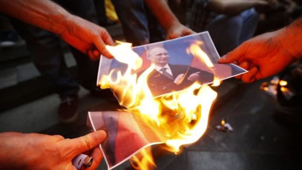Protesters burn portraits of Russian President Vladimir Putin during a rally in support of Ukraine in Tbilis.