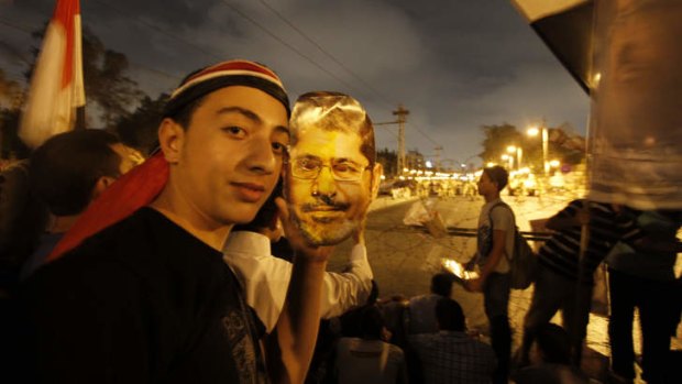 Show of face: A supporter of Egypt's ousted president Mohammed Mursi poses with a paper mask of Dr Mursi near the presidential palace in Cairo on Saturday.