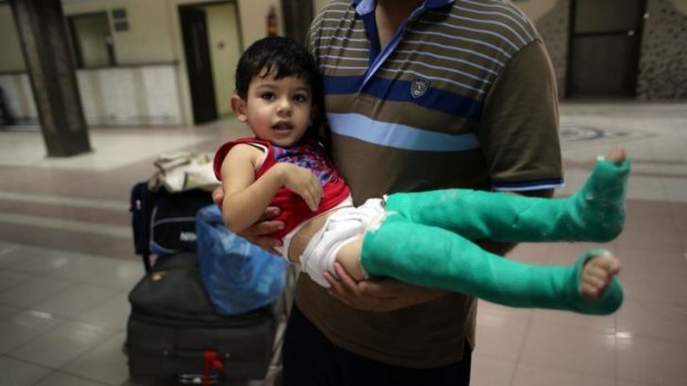 A Palestinian father carries his wounded son as they wait to cross into Egypt at the re-opened Rafah border crossing.