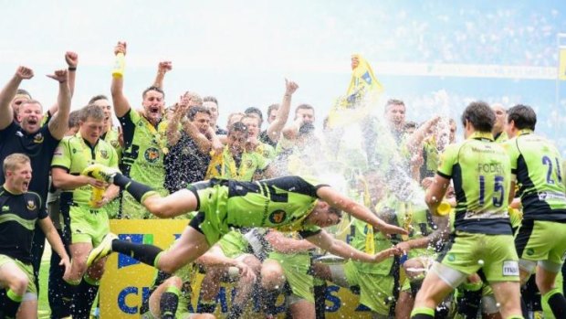 Phil Dowson of Northampton Saints dives in front of his teammates as they celebrate with the trophy.