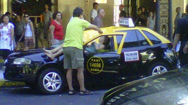 Miracle survival ... a woman lies injured  on top of a taxi after hurling herself from the 23rd floor of a hotel.