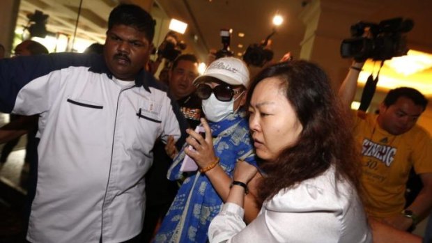 A woman, centre, is forcibly removed by security officials after she tried to protest before a press conference regarding a missing Malaysia Airlines plane at a hotel in Sepang, Malaysia.