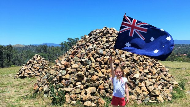 Emily flies the Australia flag at the mystery rock cairns atop Gossan Hill.