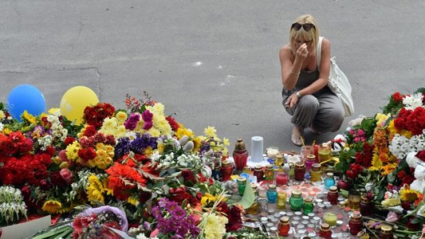 A woman crosses herself after laying flowers outside the embassy.
