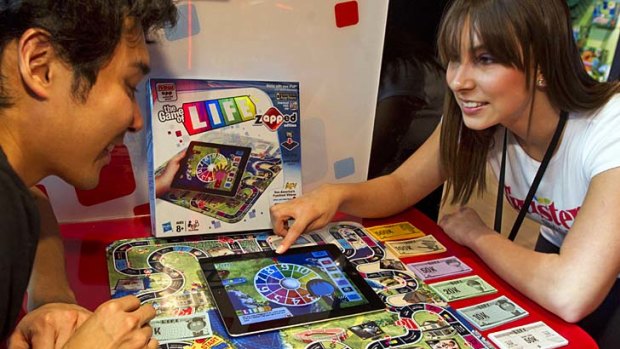 Demonstrators Trevor Zhou and Aubree Marchione use an iPad to play "The Game of Life zAPPed" at Hasbro's American International Toy Fair showroom in New York last month.