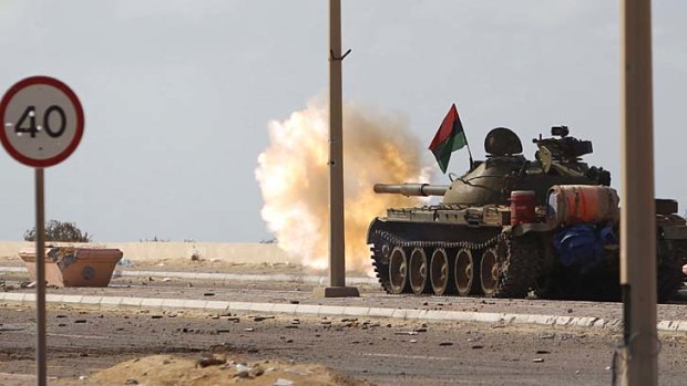 Battle rages ... anti-Gaddafi fighters fire from a tank at pro-Gaddafi forces in Sirte.