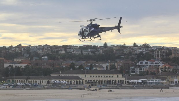A police helicopter hovers above the water at Bondi Beach.