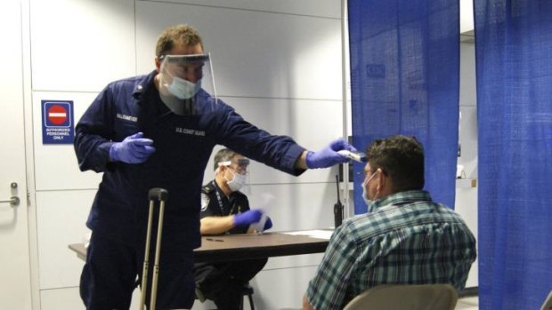 US Coast Guard and Customs officials conduct pre-screening measures on a passenger arriving from Sierra Leone at Chicago's O'Hare International Airport.