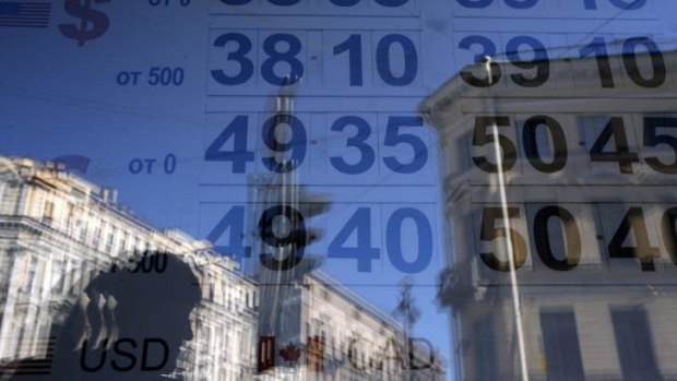 Ruble falling ... A woman is reflected in a window with a board displaying currency exchange rates in St. Petersburg.