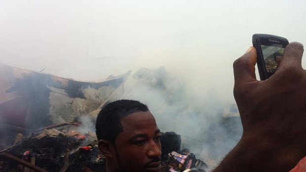 A man takes a picture of himself in front of the wreckage.
