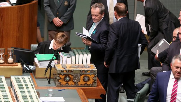 Opposition Leader Bill Shorten tries to squeeze past Prime Minister Tony Abbott to get back to his seat, after a division during question time.