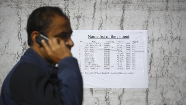 A man from a local travel agency talks to his friend on a mobile phone as he reads out names from a list showing the names of patients who were rescued from the recent avalanches and undergoing treatment at the Army hospital in Kathmandu.
