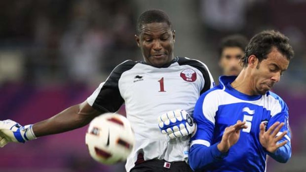 Qatar's goalkeeper Qasem Burhan (L) and Kuwait's Ahmad Ajab fight for the ball.