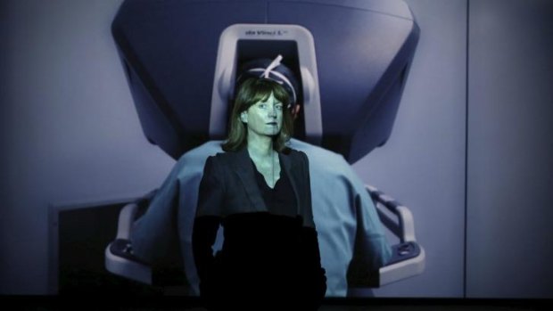 <i>People Like Us</i> curator Felicity Fenner stands in front of Yuri Ancarani's video installation of a robot performing surgery. 