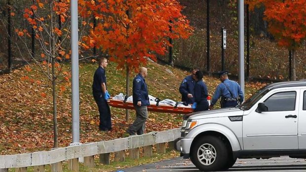 Second school tragedy in a week: investigators carry a stretcher out of the woods behind Danvers High School, Massachusetts. A 14-year-old student is in custody.