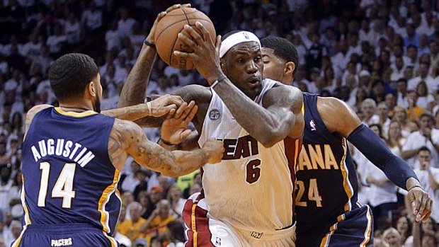 Miami's LeBron James drives between Indiana guard D.J. Augustin and forward Paul George in game five.