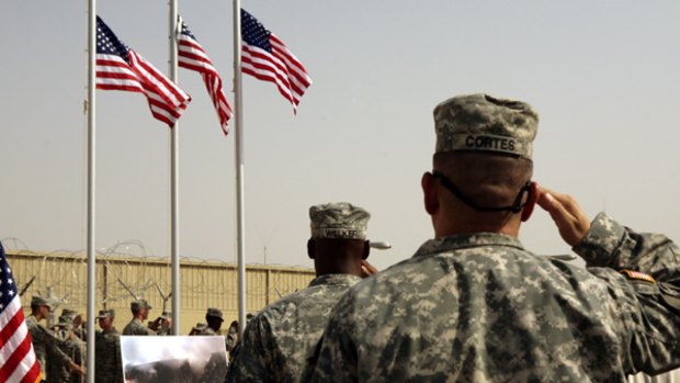 US Army soldiers salute American flags at a ceremony  at Camp Liberty in Baghdad.