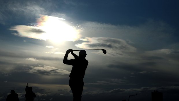 Jason Day of Australia tees off as darkness descends on St Andrews.