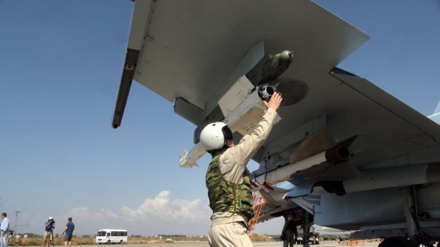 A Russian pilot fixes an air-to-air missile to his jet fighter at Hmeimim airbase in Syria. 