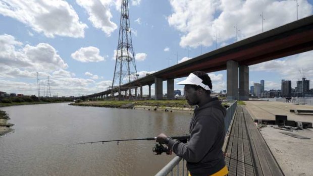 Nii Bortey, 32, goes fishing under the Bolte Bridge. Sewage has been released into Melbourne's waterways at least five times this year, sparking outrage over health risks.