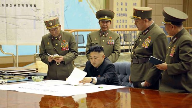 Plan of attack: Kim Jong-un with his generals on Friday. The sign on the left reads ''Strategic force's plan to hit the US mainland''.